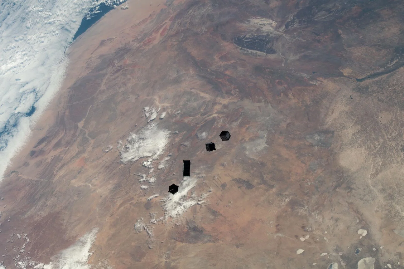 国際宇宙ステーションから放出された4基の小型キューブサットが地球上空の軌道を漂う様子