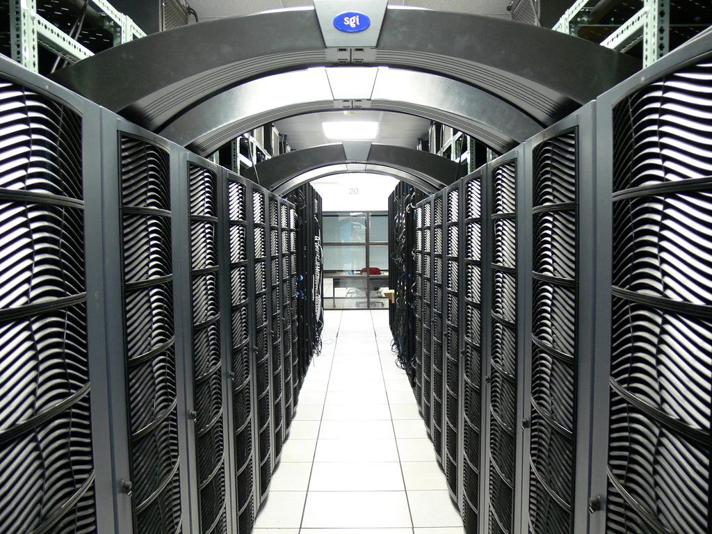 大学のデータセンターでガラス扉の奥に並ぶサーバーラック