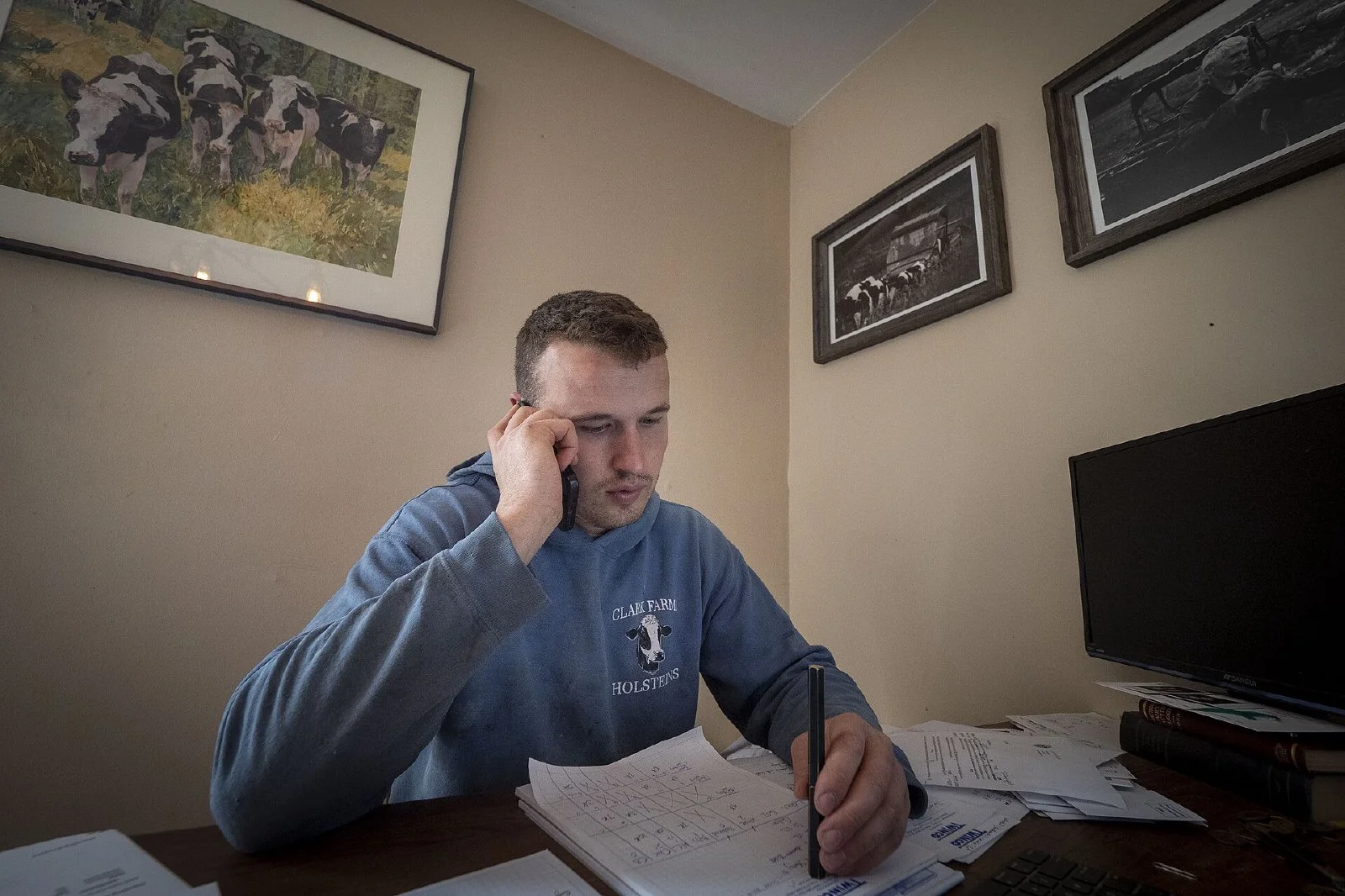 A man seated at an office desk reviewing paper documents